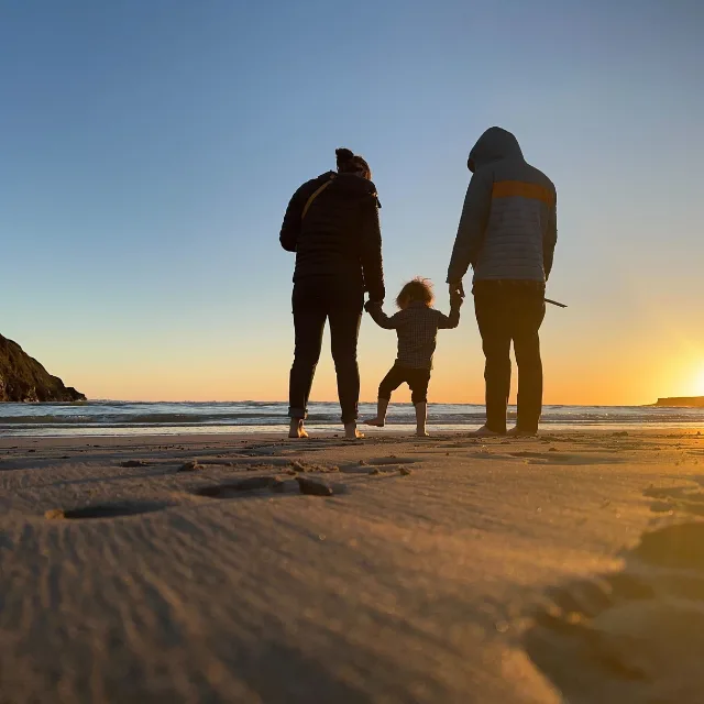 Family holding hands on a Northern California beach at sunset